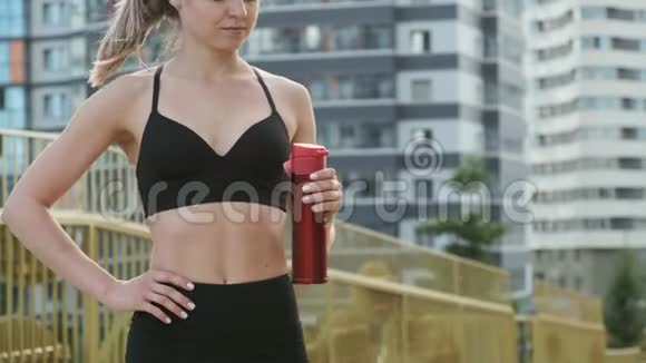 年轻的女运动员从金属瓶子里喝水视频的预览图