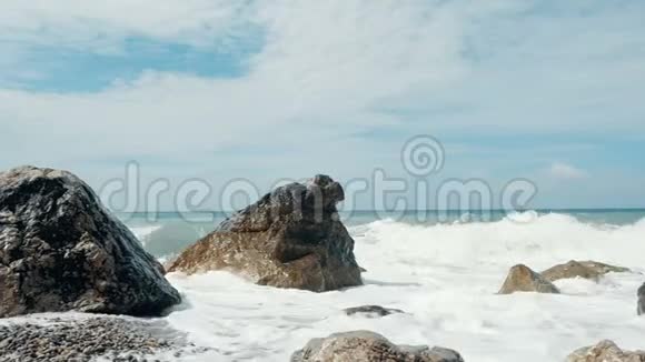巨浪撞击石头并喷洒突然溅起水花波浪在石头上折断克里米亚美丽的海滩视频的预览图
