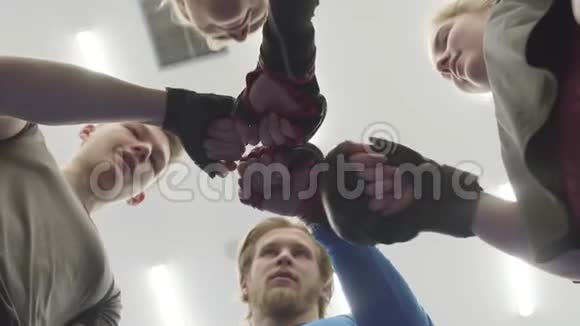四个人站在健身房摄像机上方的圆圈里一群男女运动员用拳头视频的预览图