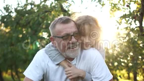 快乐的孙子们在花园里拥抱祖父孩子来到他的祖父和成年兄弟身边视频的预览图
