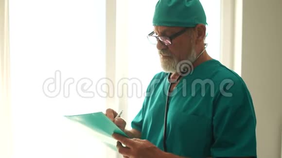 外科医生掌握着预约名单成熟的男医生有着灰色的胡须和眼镜微笑着看着视频的预览图
