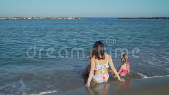 坐在沙滩上的母亲和女儿视频的预览图