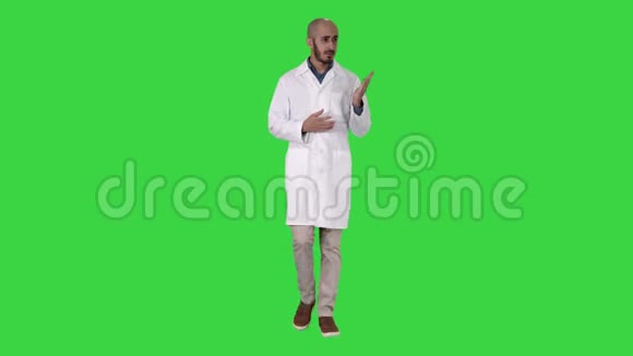 中年医生穿着医疗制服用手掌指着绿色的摄像机视频的预览图