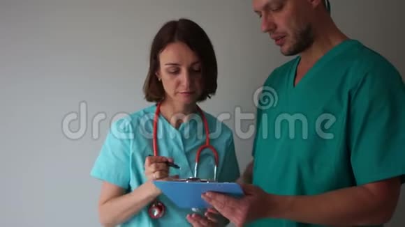 医生兼实习生医疗助理一位女医生在她年轻实习生手中的文件夹里签文件视频的预览图