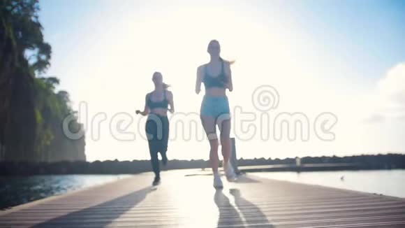 两位年轻女子在海上的桥上慢跑视频的预览图