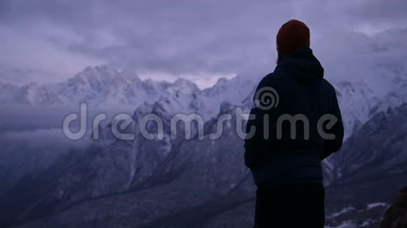 黄昏时分一位留着胡须的年轻男性旅行者在山上的肖像站着认真思考环顾四周温暖的视频的预览图