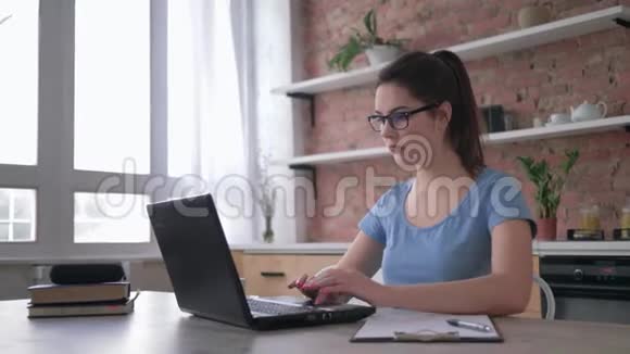 教育戴眼镜的女学生早上使用电脑笔记本电脑喝白咖啡然后写笔记视频的预览图