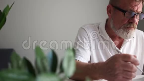成熟的男人和电脑爷爷戴着眼镜胡子灰白忙着靠近笔记本电脑盯着屏幕打字视频的预览图