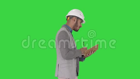 阿拉伯男子穿休闲服装和安全帽写下清单上的绿色屏幕铬键视频的预览图