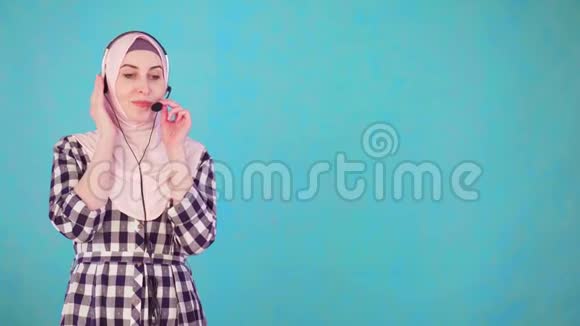 年轻漂亮的穆斯林妇女带着电话耳机交流视频的预览图