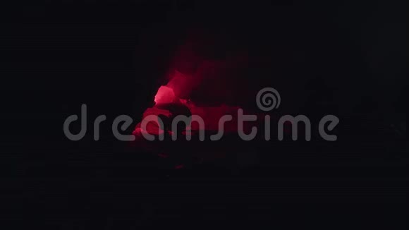 一个人在黑暗中探索一个有红色燃烧信号耀斑的洞穴的剪影库存录像男性视频的预览图