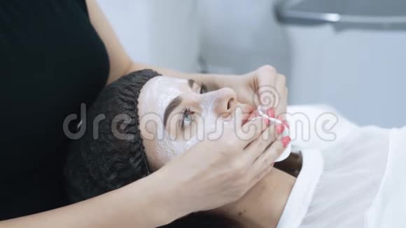 将美容师的双手从年轻女子的脸上取下化妆面具动作缓慢视频的预览图