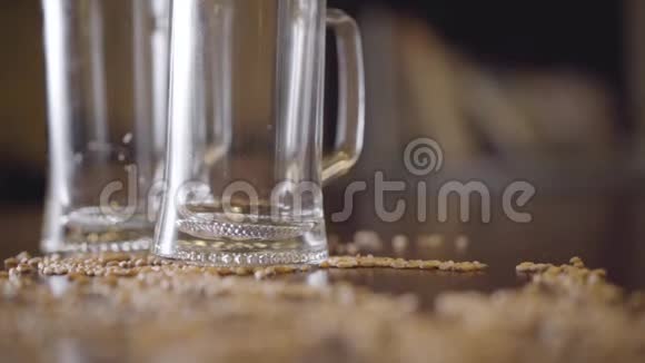 两杯空啤酒放在吧台上特写镜头把第三个杯子放在桌子上的男性手大麦视频的预览图