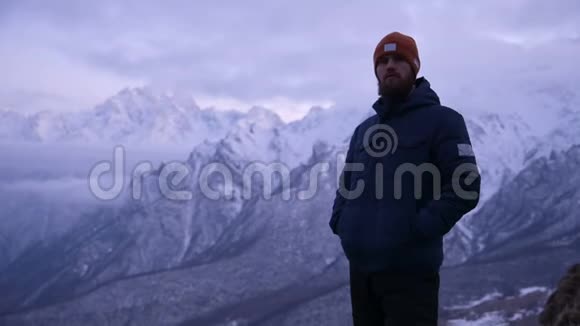 黄昏时分一位留着胡须的年轻男性旅行者在山上的肖像站着认真思考环顾四周温暖的视频的预览图