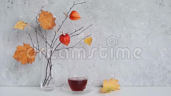 喝茶的时候茶杯和秋天的创意花束树枝上挂着黄色的叶子花瓶插在桌上视频的预览图