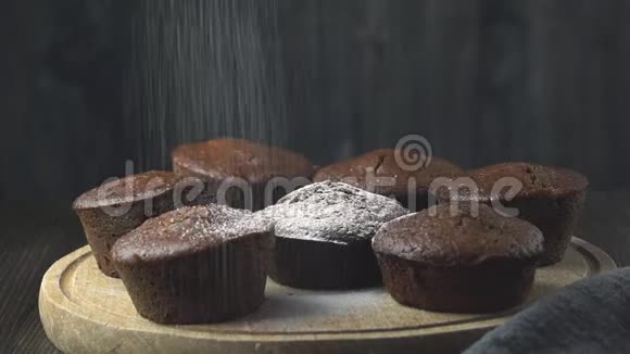 面包师在美味的巧克力松饼上撒粉糖霜视频的预览图