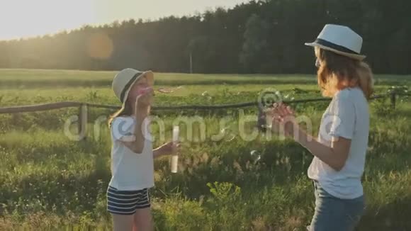 孩子们吹肥皂泡两个女孩在大自然中玩耍视频的预览图