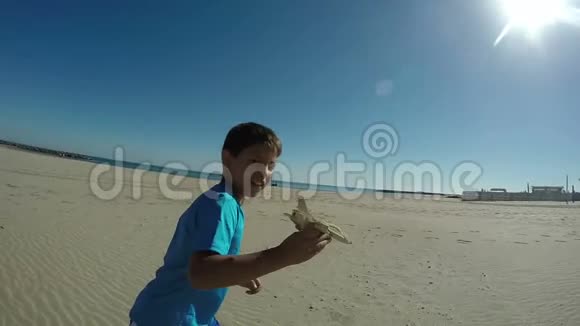 快乐男孩在海滩上玩模型飞机视频的预览图