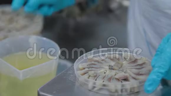 近镜头女职工手把油从一个塑料罐子倒入一罐鱼保护区鱼类生产视频的预览图