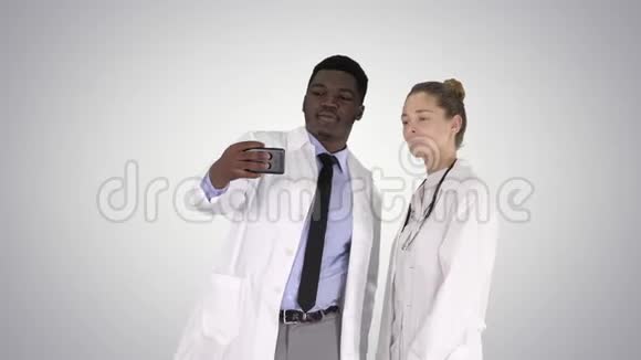 两位医生正在使用智能手机自拍并在梯度背景上微笑视频的预览图