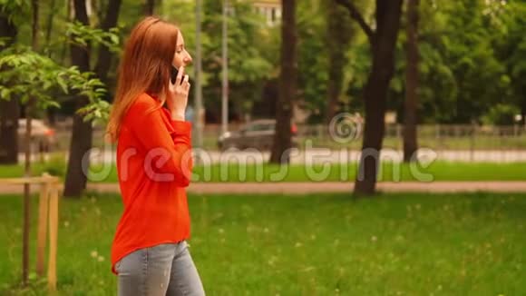 红头发的女商人在路上通过电话交谈视频的预览图