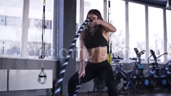 强壮的有动力的积极的女人在交叉训练锻炼中在健身房中与绳索搏斗慢动作视频的预览图