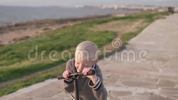 有趣的金发男孩骑着滑板车沿着长廊视频的预览图