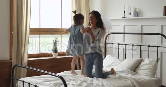 可爱活泼的小女孩在床上和妈妈玩耍视频的预览图