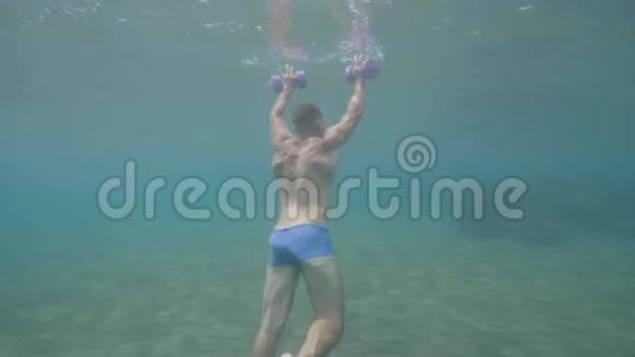 男子游泳运动员正在水下用哑铃训练后视视频的预览图
