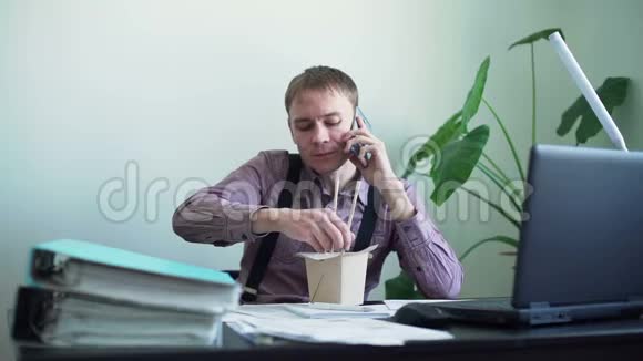 男人在办公室吃面条在电话里聊天视频的预览图