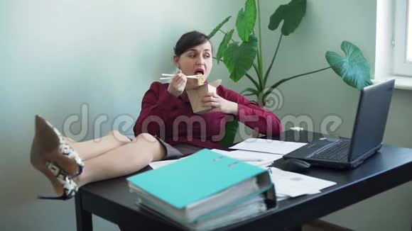 办公桌上有腿的妇女在工作期间吃午餐视频的预览图