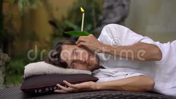 一个在热带花园里的年轻人耳朵里放着耳烛视频的预览图