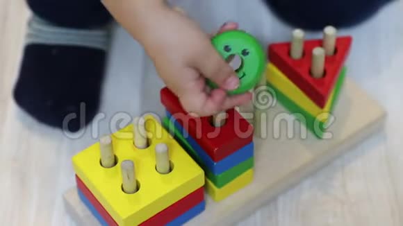 一个一岁的孩子在木制建筑中把几何形状放在别针上儿童的手和玩具特写视频的预览图