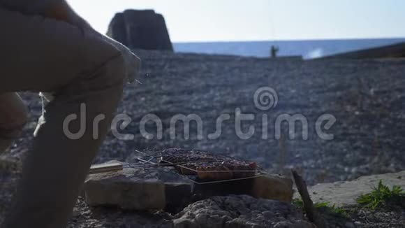 用海边岩石做的临时烤架烤制的肉视频的预览图