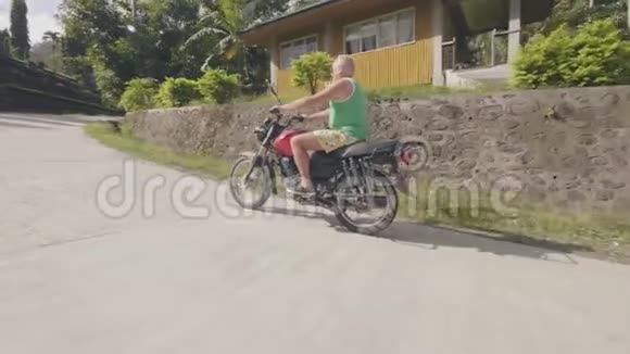 一名骑摩托车的男子在棕榈树背景的乡村公路上骑摩托车高级摩托车骑手视频的预览图