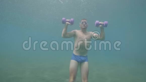 年轻的运动运动员戴着面具正在水下用哑铃做肩膀练习正面观看视频的预览图