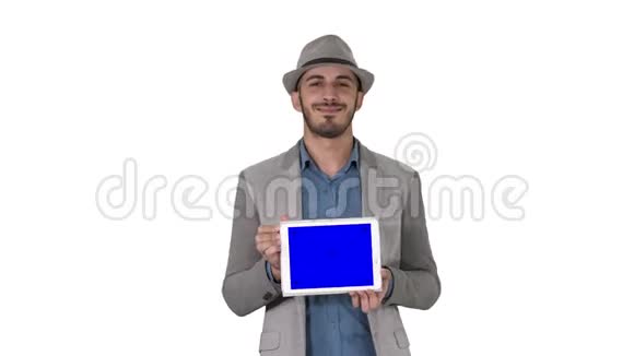 戴着帽子的闲人走着在白色背景上向摄像机展示数字平板电脑视频的预览图