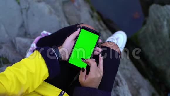 年轻迷人的女孩用她的智能手机用绿色屏幕染色模型VFX稳定镜头特写视频的预览图