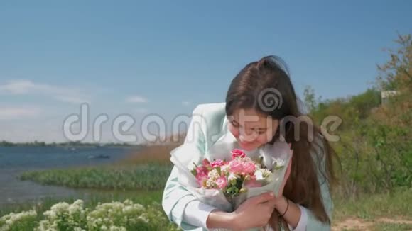 喜笑颜开的女人在河边的草地上绽放着美丽的鲜花视频的预览图
