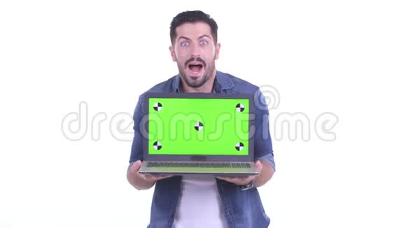快乐的年轻留胡子的时髦男人带着笔记本电脑看上去很惊讶视频的预览图