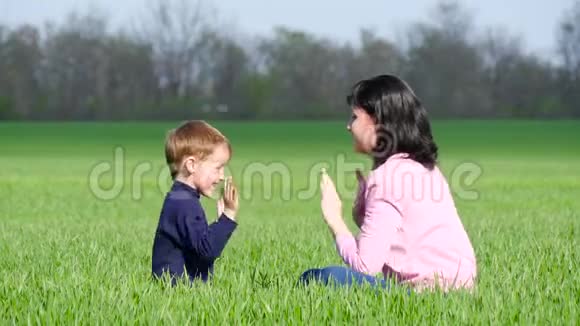 快乐的孩子和妈妈在公园的草地上玩耍拥抱和亲吻视频的预览图