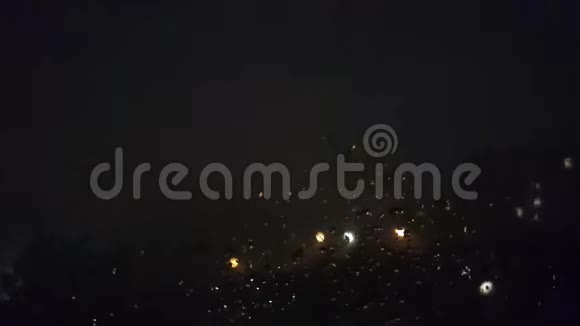 在夜晚城市灯光的映衬下窗玻璃上流淌着雨水视频的预览图