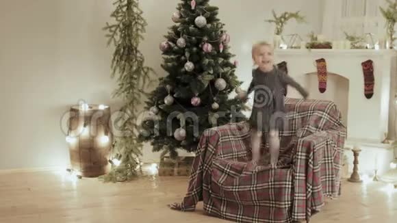 在圣诞节装饰的背景下小女孩跳上了新年的椅子视频的预览图