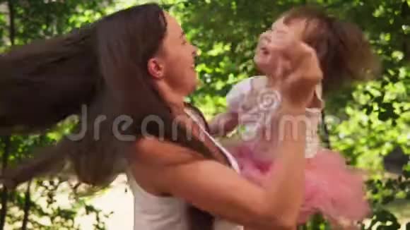 快乐的妈妈拥抱可爱的小女儿和她在阳光明媚的公园里嬉戏视频的预览图