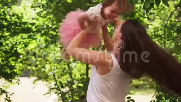 快乐的妈妈在阳光明媚的夏日公园里和宝宝旋转视频的预览图