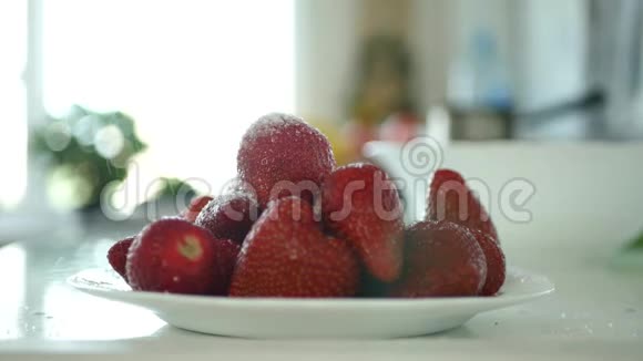 男人手把白糖粉放在装满草莓水果的盘子里视频的预览图
