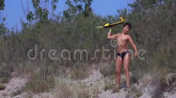 男孩在海滩上玩飞机模型视频的预览图