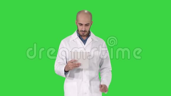 成熟的男性医生拿着数字平板电脑使用它走在绿色屏幕上Chroma键视频的预览图