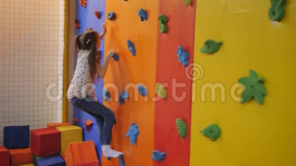 七岁的女孩在爬墙蹦床中心爬行视频的预览图