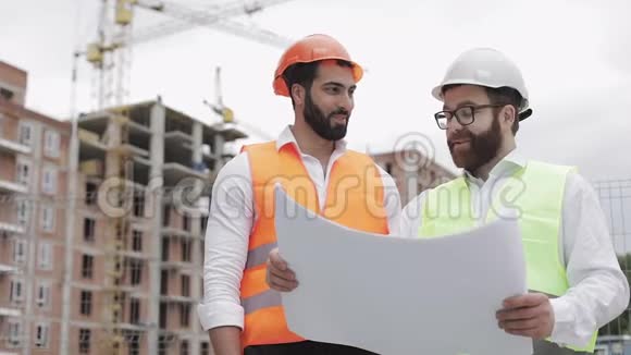 在建筑工地或高层建筑工地与建筑师微笑男建筑工程师讨论视频的预览图